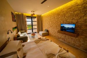 a bedroom with a bed and a tv on a wall at BABERRIH Hôtel Hospitality Palaces & Resorts in Essaouira