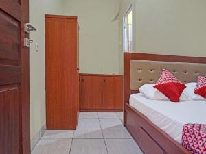 a bedroom with a bed with red and white pillows at OYO 91649 Orange Homestay Makassar in Makassar