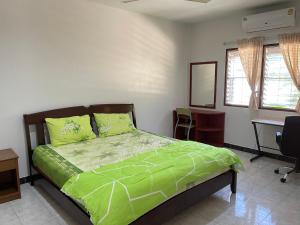 a bedroom with a bed with a green comforter and a desk at H&Q 1BR Cozy House, Bangtao Beach in Ban Thalat Choeng Thale