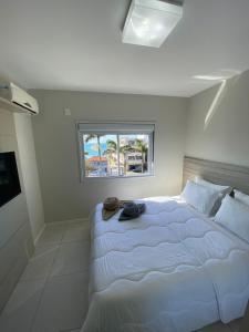 a bedroom with a large white bed with a window at Paradise in Florianópolis