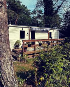 a white caravan with a wooden fence and a tree at Knus chalet midden in de bossen in Nunspeet