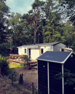 een klein huisje in een tuin met een schuur bij Knus chalet midden in de bossen in Nunspeet