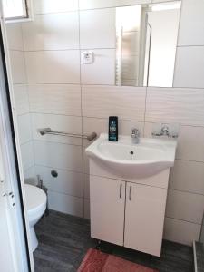 a white bathroom with a sink and a mirror at Vaš Kutak - Sobe Lux za izdavanje in Obrenovac