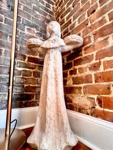 een standbeeld van een vrouw die tegen een stenen muur leunt bij Be Our Gaston's "The Garden of Good" in Savannah
