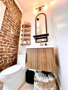 a bathroom with a white toilet and a brick wall at Be Our Gaston's "The Garden of Good" in Savannah