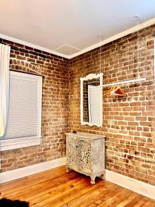 a room with a brick wall and a wooden floor at Be Our Gaston's "The Garden of Good" in Savannah