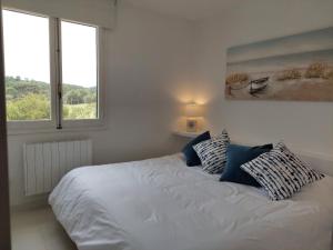 1 cama blanca con almohadas en un dormitorio con 2 ventanas en Apartamento Son Parc Menorca, en Son Parc