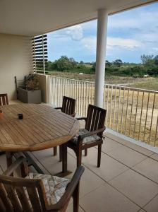 a porch with a wooden table and chairs on a balcony at Appartement T2 sur Mauguio avec grande terrasse in Mauguio