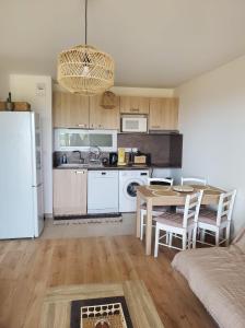 uma cozinha com uma mesa e um frigorífico branco em Appartement T2 sur Mauguio avec grande terrasse em Mauguio