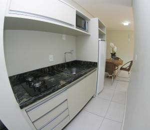 a white kitchen with a sink and a refrigerator at Paradise in Florianópolis
