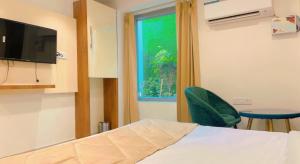 ein Schlafzimmer mit einem Bett, einem grünen Stuhl und einem Fenster in der Unterkunft City View With Garden -5 Mins Walk From GOLDEN TEMPLE in Amritsar