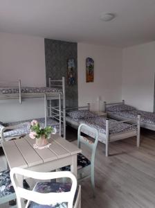 Henryków LubańskiにあるDom Miliの二段ベッド3台、テーブル、椅子が備わる客室です。