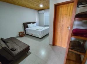 a room with a bed and a couch and a door at Flat dos Bandeirantes in Tiradentes