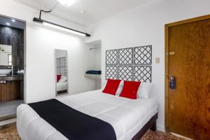 1 dormitorio con 1 cama blanca grande con almohadas rojas en Hotel La Colección, Universidad de Guanajuato, Centro en Guanajuato