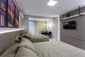 two beds in a hotel room with a tv at Apart Hotel Centro de Brasília in Brasilia