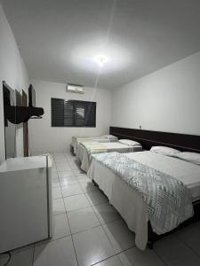 a room with three beds in it with a window at Residence Hotel Ltda in Paiçandu