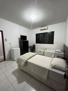 a bedroom with two beds and a television in it at Residence Hotel Ltda in Paiçandu