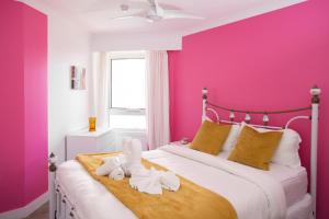 a pink bedroom with a bed with towels on it at Beachfront Romantic Getaway - Surfers Paradise in Gold Coast