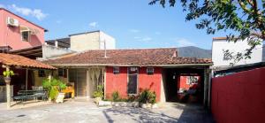 a red brick house with a red fence in front of it at Hostel Canto da Praia São Sebastião - próximo ao enrocamento Caraguatatuba in São Sebastião