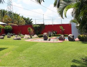 a garden with rocks and a red fence at Preciosa Casa Palmera en Cuernavaca con Alberca, Wifi, TV y Cocina Para fin de semana, descanso, vacaciones o Home office in Emiliano Zapata