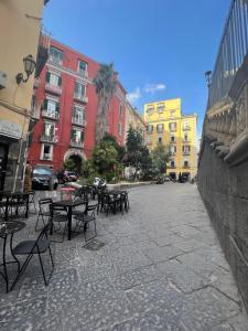 un gruppo di tavoli e sedie su una strada con edifici di La Nova apartment a Napoli
