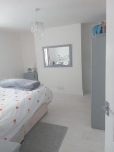 a white bedroom with a bed and a mirror at 29a Margate in Kent