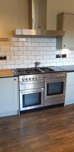 um fogão de aço inoxidável numa cozinha com azulejos brancos em The Cob House. em Ifton Heath