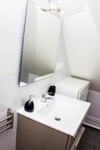 y baño con lavabo blanco y espejo. en F2 Duplex chez l'aventurière près Disneyland, en Roissy-en-Brie