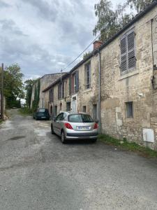 un coche aparcado frente a un edificio de piedra en Charmant appartement avec SPA, en Fontenay-le-Comte