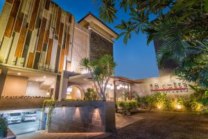 a building with palm trees in front of it at 18 Suite Villa Loft at Kuta in Kuta