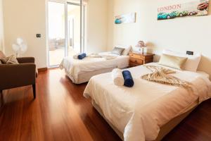 ein Schlafzimmer mit zwei Betten, einem Stuhl und einem Fenster in der Unterkunft Bellevue Villa Madeira Magnificent Sea View in Prazeres + 35 Fotos