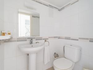 a white bathroom with a toilet and a sink at Marina nº 5 in Puerto de Mogán +36 photos