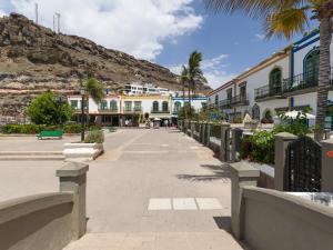 a street with buildings and palm trees and a mountain at Marina nº 5 in Puerto de Mogán