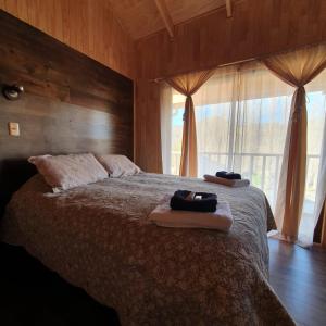 1 dormitorio con 1 cama con 2 toallas en Cabañas El Maiten, en Puerto Guadal