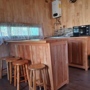 a kitchen with a bar with wooden stools at Cabañas El Maiten in Puerto Guadal