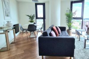ein Wohnzimmer mit einer Couch und einem Tisch mit Stühlen in der Unterkunft City Centre 2 Bedroomed Apartment - Great views - wifi in Sheffield