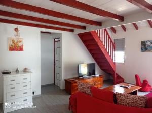 a living room with a red couch and a staircase at "Le champs" des oiseaux in Anse-Bertrand