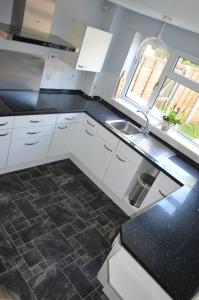 a kitchen with white cabinets and a sink and a window at Cheerful 3 bedroom property set in the countryside in Westcott