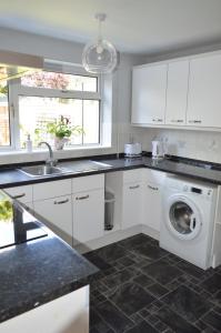 a kitchen with a washer and a sink and a washing machine at Cheerful 3 bedroom property set in the countryside in Westcott