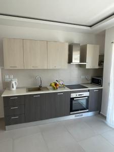 een keuken met grijze kasten, een wastafel en een fornuis bij New & Comfortable 7SUN Apartments near sandy beach in St Paul's Bay