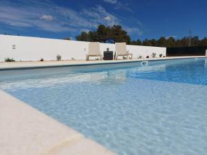 - une piscine avec 2 chaises blanches à côté dans l'établissement Eagle House, à Sao Pedro de Tomar