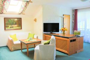 uma sala de estar com uma televisão e uma mesa e cadeiras em Kurhotel Schlossberghof Marzoll em Bad Reichenhall