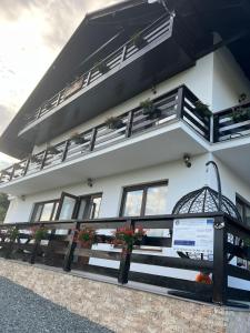un bâtiment blanc avec des fenêtres et des plantes. dans l'établissement Pensiunea Agroturistica Acvila Apusenilor, à Vadu Moţilor