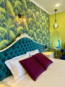 a bedroom with a bed with a blue head board at Palm View Guesthouse, adults only in Luz
