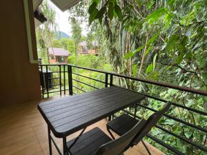 a wooden table and two chairs on a balcony at Khaosok Rainforest Resort in Khao Sok National Park