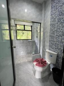 a bathroom with a toilet with a pink towel on it at Khaosok Rainforest Resort in Khao Sok National Park