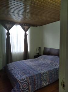 a bedroom with a bed with a blue blanket and a window at Mirador del parque in Bogotá