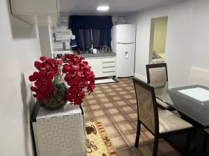 a kitchen with a table with a vase of red flowers at Linda Casa 3 qts prox JK Shopping in Brasília