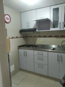 a kitchen with white cabinets and a sink and a stove at Mirador del parque in Bogotá