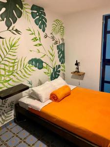 a bedroom with a bed with orange sheets and plants on the wall at Walker's House Hostel in Salento